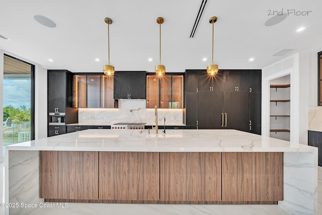 16 Seaside Ave, Key Largo, FL 33037 - kitchen with backsplash, a large island with sink, light stone counters, recessed lighting, and glass insert cabinets