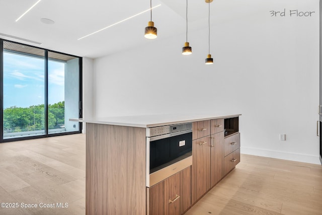16 Seaside Ave, Key Largo, FL 33037 - kitchen featuring floor to ceiling windows, light wood-style flooring, modern cabinets, decorative light fixtures, and oven