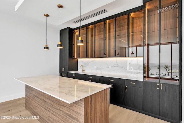 16 Seaside Ave, Key Largo, FL 33037 - kitchen featuring decorative backsplash, dark cabinets, light wood-style floors, and a center island