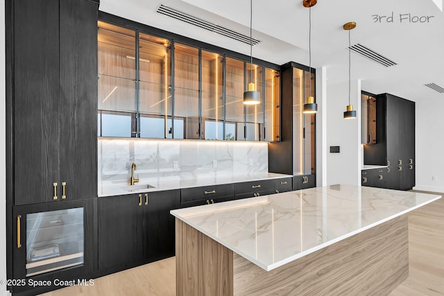 16 Seaside Ave, Key Largo, FL 33037 - kitchen with dark cabinets, light stone counters, decorative light fixtures, a center island, and modern cabinets