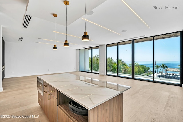 16 Seaside Ave, Key Largo, FL 33037 - kitchen with floor to ceiling windows, light wood-style floors, open floor plan, light stone countertops, and decorative light fixtures