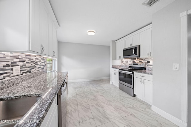 959 Macco Rd, Cocoa, FL 32927 - kitchen featuring stainless steel appliances, light marble finish floors, dark stone counters, and decorative backsplash