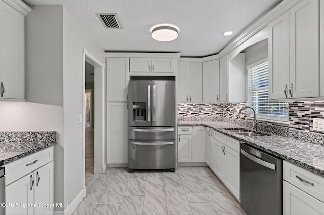 959 Macco Rd, Cocoa, FL 32927 - kitchen featuring stainless steel appliances, light marble finish floors, tasteful backsplash, white cabinets, and a textured ceiling
