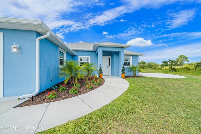 156 Puddle Duck Ln, Grant-Valkaria, FL 32909 - view of exterior entry featuring a lawn, stucco siding, and roof with shingles