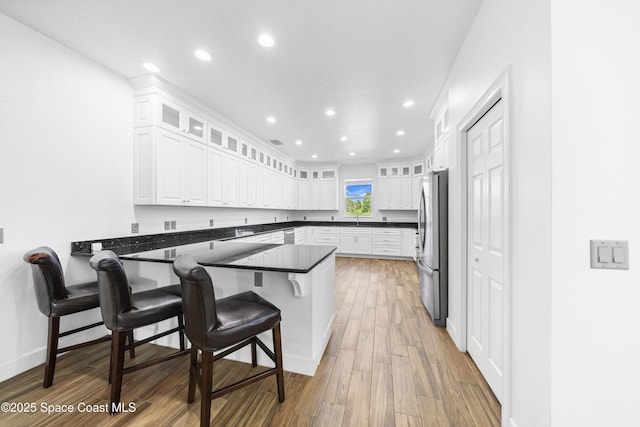156 Puddle Duck Ln, Grant-Valkaria, FL 32909 - kitchen with a peninsula, freestanding refrigerator, light wood finished floors, white cabinets, and recessed lighting