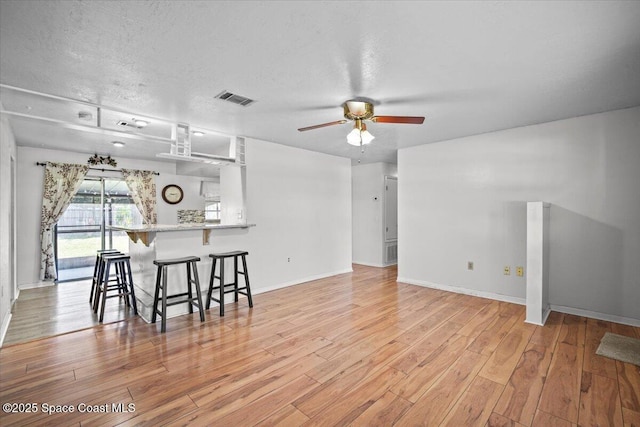 3664 Longbow Rd, Cocoa, FL 32926 - kitchen featuring a kitchen bar, ceiling fan, light wood-style floors, a textured ceiling, and a peninsula