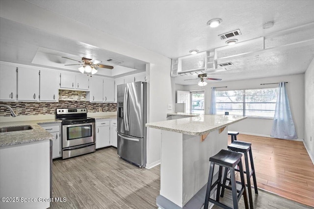 3664 Longbow Rd, Cocoa, FL 32926 - kitchen featuring appliances with stainless steel finishes, a ceiling fan, a tray ceiling, light stone countertops, and light wood finished floors