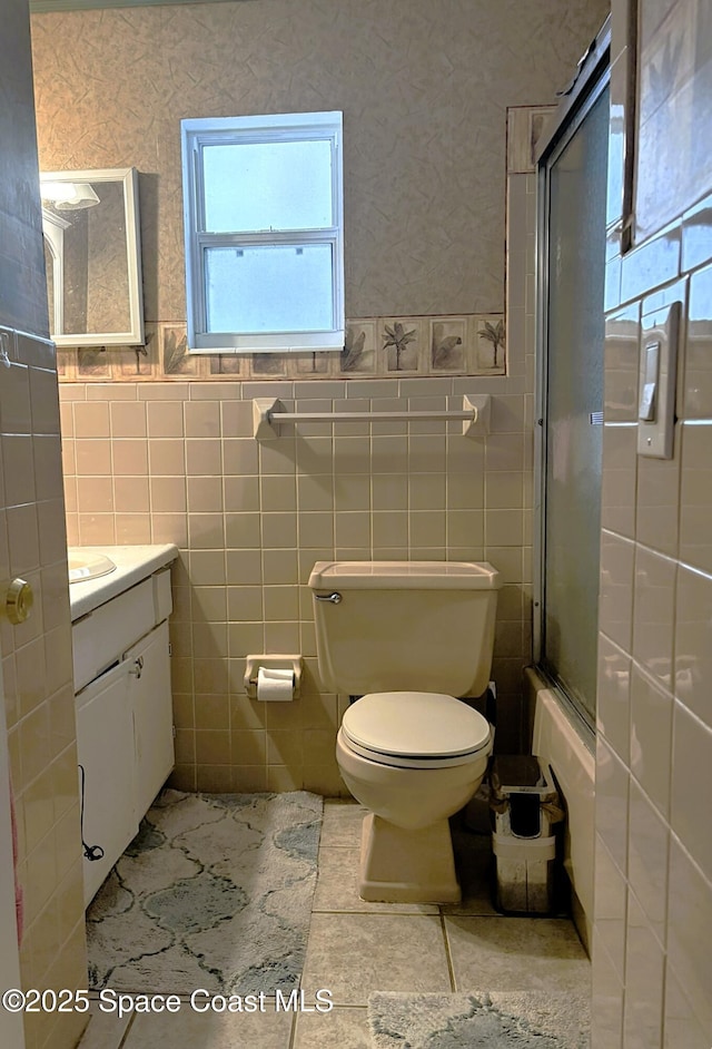 292 Pine Tree Dr, Indialantic, FL 32903 - full bath featuring plenty of natural light, tile walls, vanity, enclosed tub / shower combo, and tile patterned flooring