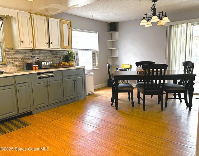 292 Pine Tree Dr, Indialantic, FL 32903 - dining area featuring plenty of natural light, light wood finished floors, a chandelier, and a textured ceiling