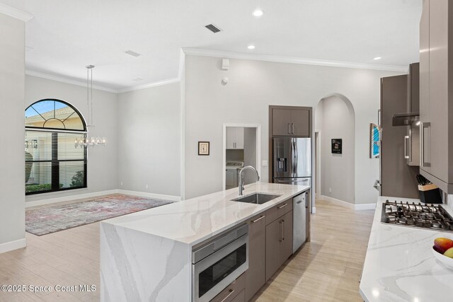 7987 Bradwick Way, Melbourne, FL 32940 - kitchen featuring stainless steel appliances, arched walkways, ornamental molding, light wood-style floors, and light stone countertops