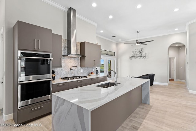 7987 Bradwick Way, Melbourne, FL 32940 - kitchen with appliances with stainless steel finishes, wall chimney range hood, arched walkways, gray cabinetry, and crown molding