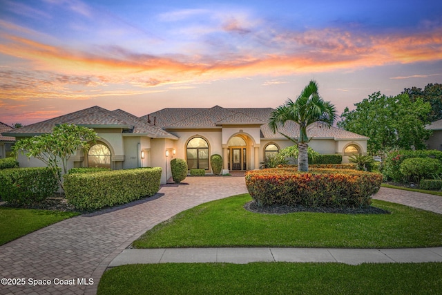 7987 Bradwick Way, Melbourne, FL 32940 - mediterranean / spanish-style home with stucco siding, a yard, and curved driveway