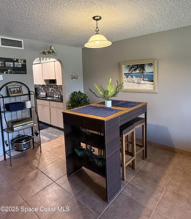 520 Palm Springs Blvd Unit 102, Indian Harbour Beach, FL 32937 - dining area with arched walkways, dark tile patterned flooring, and a textured ceiling