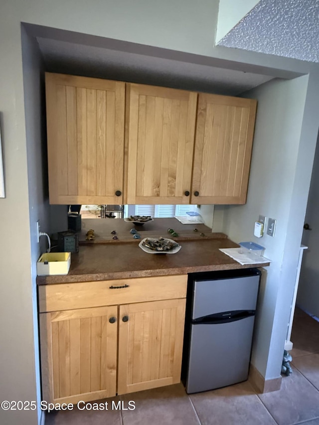 520 Palm Springs Blvd Unit 102, Indian Harbour Beach, FL 32937 - kitchen featuring light brown cabinetry, refrigerator, light tile patterned flooring, and dark countertops