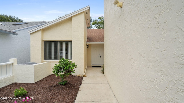 1734 Bluebird Ct, Melbourne, FL 32935 - doorway to property with stucco siding and roof with shingles