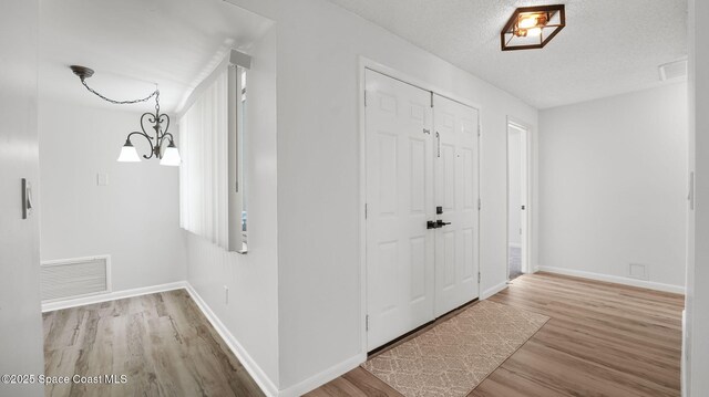1734 Bluebird Ct, Melbourne, FL 32935 - foyer entrance featuring wood finished floors, a chandelier, and a textured ceiling