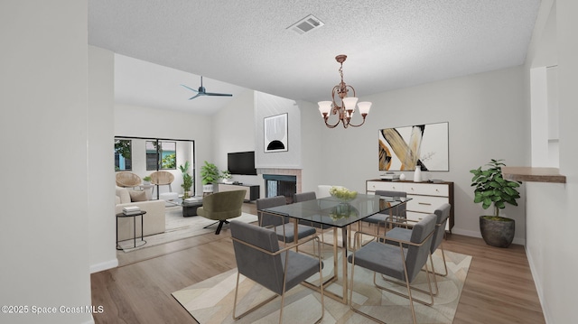 1734 Bluebird Ct, Melbourne, FL 32935 - dining space with a fireplace, wood finished floors, a chandelier, a textured ceiling, and vaulted ceiling