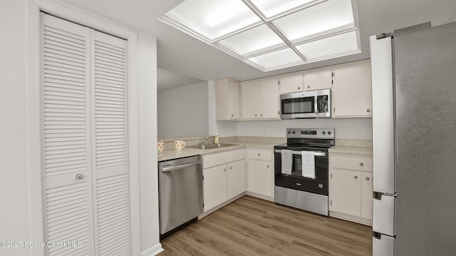 1734 Bluebird Ct, Melbourne, FL 32935 - kitchen with appliances with stainless steel finishes, light wood-type flooring, light countertops, and white cabinets