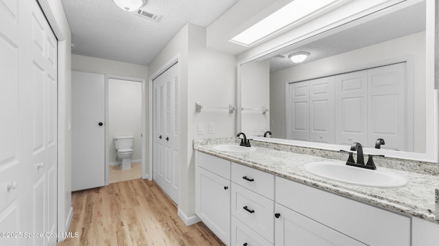 1734 Bluebird Ct, Melbourne, FL 32935 - bathroom with a closet, double vanity, wood finished floors, and a textured ceiling