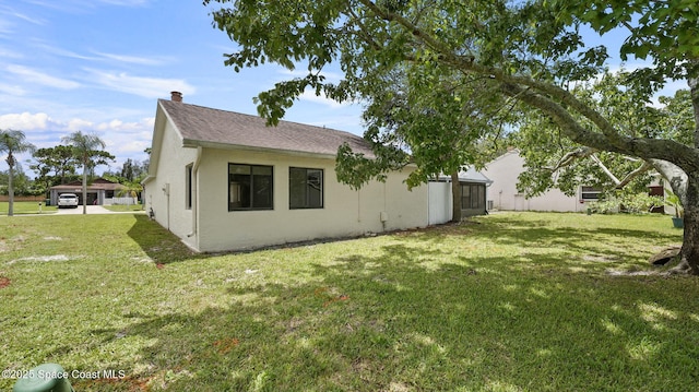 1734 Bluebird Ct, Melbourne, FL 32935 - view of side of property with a lawn, stucco siding, and a chimney