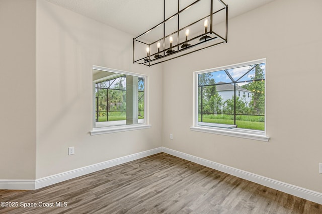 8025 Babcock St SE, Grant-Valkaria, FL 32909 - empty room with wood finished floors, plenty of natural light, and a chandelier