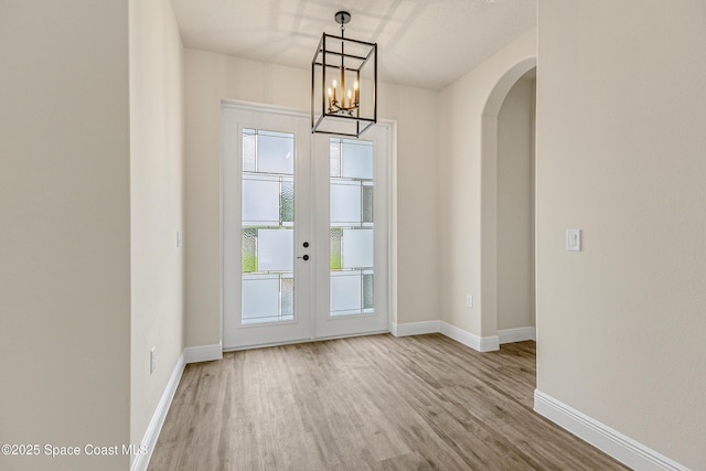 8025 Babcock St SE, Grant-Valkaria, FL 32909 - unfurnished dining area featuring arched walkways, wood finished floors, french doors, and a chandelier