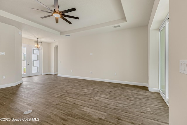 8025 Babcock St SE, Grant-Valkaria, FL 32909 - empty room with a tray ceiling, arched walkways, dark wood-style flooring, ceiling fan, and a chandelier
