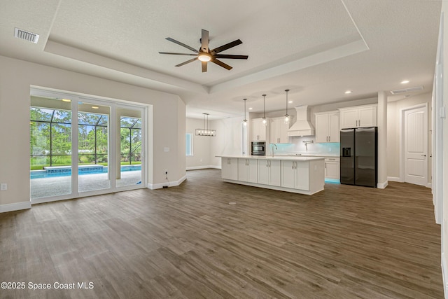 8025 Babcock St SE, Grant-Valkaria, FL 32909 - kitchen featuring appliances with stainless steel finishes, a raised ceiling, premium range hood, open floor plan, and light countertops