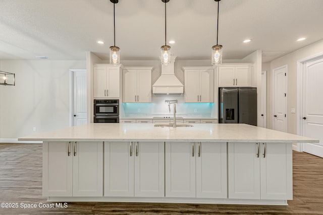 8025 Babcock St SE, Grant-Valkaria, FL 32909 - kitchen with appliances with stainless steel finishes, a large island with sink, white cabinetry, wood finished floors, and recessed lighting