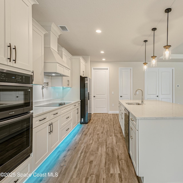 8025 Babcock St SE, Grant-Valkaria, FL 32909 - kitchen featuring stainless steel appliances, white cabinetry, light wood-style flooring, decorative light fixtures, and recessed lighting
