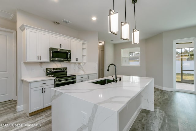 8025 Babcock St SE, Grant-Valkaria, FL 32909 - kitchen featuring stainless steel microwave, range with electric stovetop, open shelves, white cabinets, and light wood-type flooring