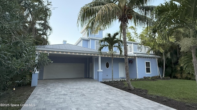 210 Pelican Dr, Melbourne Beach, FL 32951 - view of front of house with an attached garage, a front lawn, decorative driveway, and a metal roof
