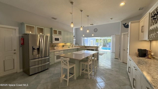210 Pelican Dr, Melbourne Beach, FL 32951 - kitchen featuring white appliances, a peninsula, a kitchen bar, decorative backsplash, and glass insert cabinets