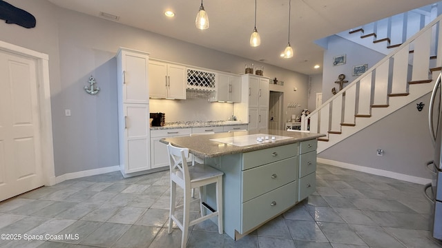 210 Pelican Dr, Melbourne Beach, FL 32951 - kitchen featuring white cabinetry, a kitchen island, tile patterned floors, decorative light fixtures, and light stone counters