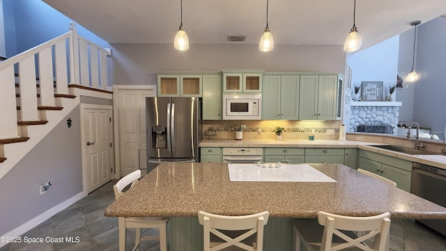 210 Pelican Dr, Melbourne Beach, FL 32951 - kitchen with green cabinetry, stainless steel appliances, a breakfast bar, and decorative backsplash