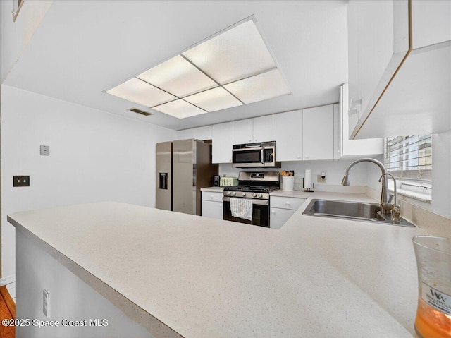 3116 Winchester Dr, Cocoa, FL 32926 - kitchen with stainless steel appliances, light countertops, white cabinetry, and a peninsula