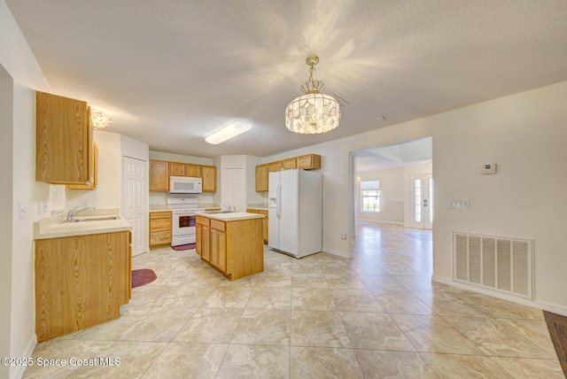 6065 Balboa St, Cocoa, FL 32927 - kitchen with white appliances, a textured ceiling, a center island, light countertops, and a chandelier