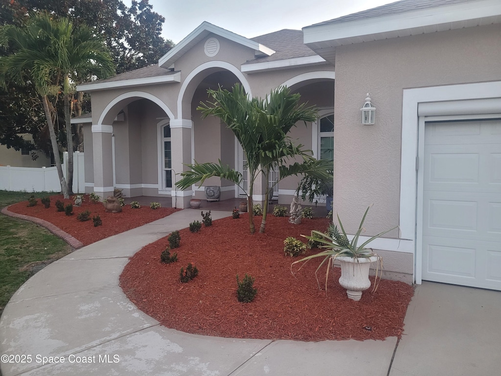 401 Stonehenge Cir, Rockledge, FL 32955 - view of exterior entry with stucco siding, an attached garage, and a shingled roof