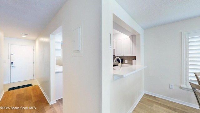 3799 S Banana River Blvd Unit 1025, Cocoa Beach, FL 32931 - hallway featuring light wood-type flooring, a textured ceiling, and healthy amount of natural light