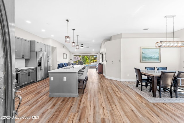1218 Rolling Meadows Dr, Rockledge, FL 32955 - kitchen with gray cabinets, appliances with stainless steel finishes, light wood-style floors, light countertops, and an island with sink