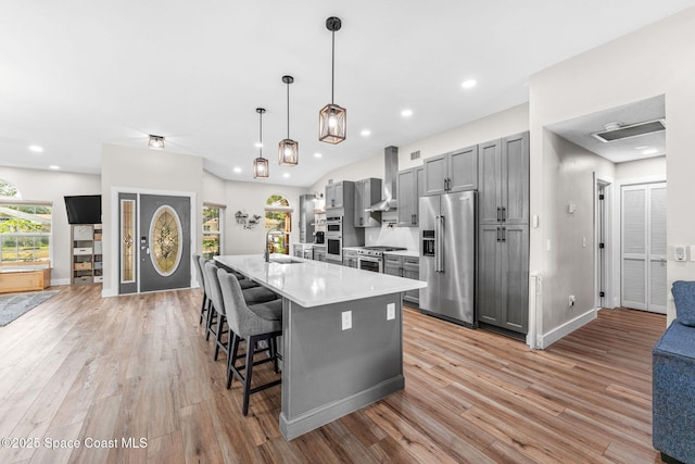 1218 Rolling Meadows Dr, Rockledge, FL 32955 - kitchen with stainless steel appliances, gray cabinets, wall chimney range hood, light countertops, and a center island with sink