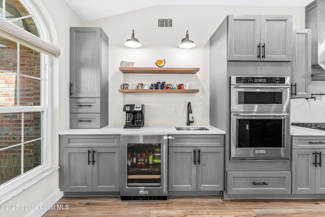 1218 Rolling Meadows Dr, Rockledge, FL 32955 - indoor wet bar featuring wine cooler, double oven, plenty of natural light, and light wood finished floors