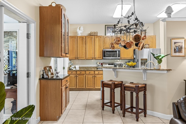 4595 Alan Shepard Ave, Cocoa, FL 32926 - kitchen featuring stainless steel appliances, a breakfast bar area, dark stone counters, decorative backsplash, and glass insert cabinets
