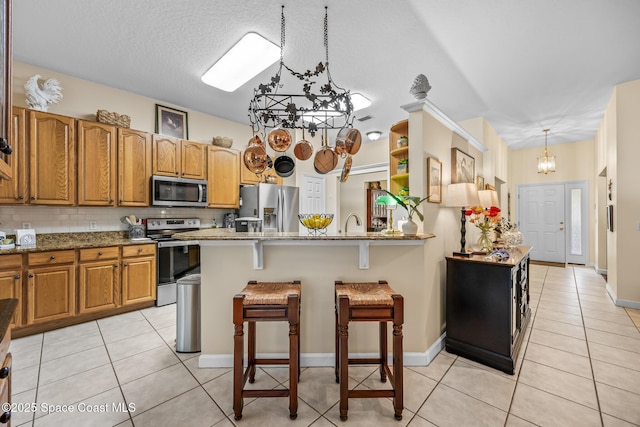 4595 Alan Shepard Ave, Cocoa, FL 32926 - kitchen with stainless steel appliances, a chandelier, a breakfast bar area, and light tile patterned floors
