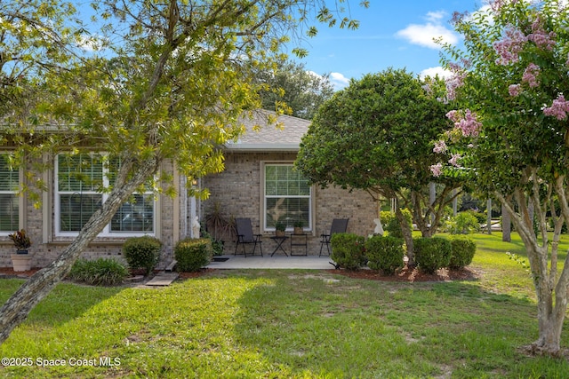 4595 Alan Shepard Ave, Cocoa, FL 32926 - obstructed view of property with brick siding, a front lawn, a patio area, and roof with shingles