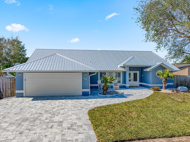 100 Matthews St, Satellite Beach, FL 32937 - ranch-style home with french doors, a metal roof, an attached garage, decorative driveway, and stucco siding