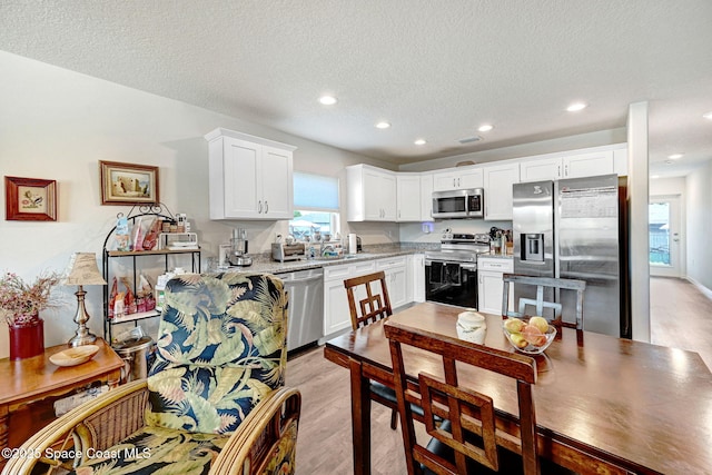 1689 Colorado St SE, Palm Bay, FL 32909 - kitchen with appliances with stainless steel finishes, recessed lighting, white cabinets, a textured ceiling, and light wood-style floors
