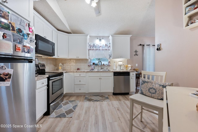 6640 Dock Ave, Cocoa, FL 32927 - kitchen featuring stainless steel appliances, white cabinetry, a textured ceiling, light wood-style floors, and backsplash