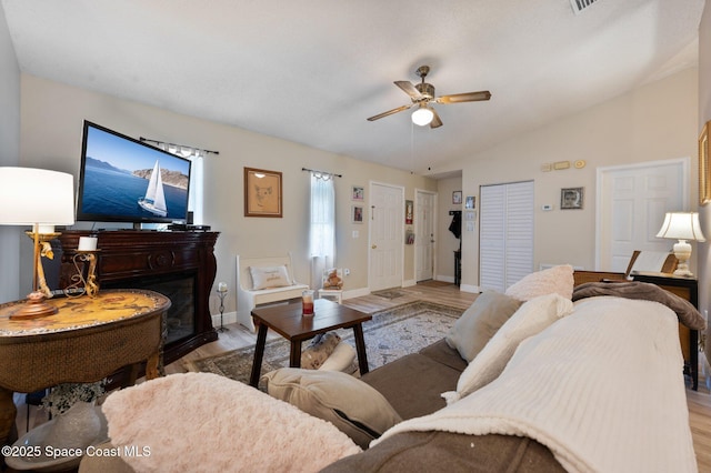 6640 Dock Ave, Cocoa, FL 32927 - living area with light wood-type flooring, a ceiling fan, vaulted ceiling, and a glass covered fireplace