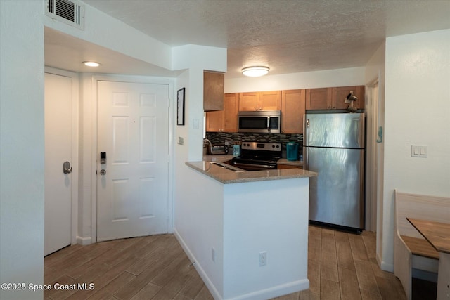 1951 Island Club Dr Unit 3-48, Melbourne, FL 32903 - kitchen featuring appliances with stainless steel finishes, wood tiled floors, a peninsula, backsplash, and a textured ceiling